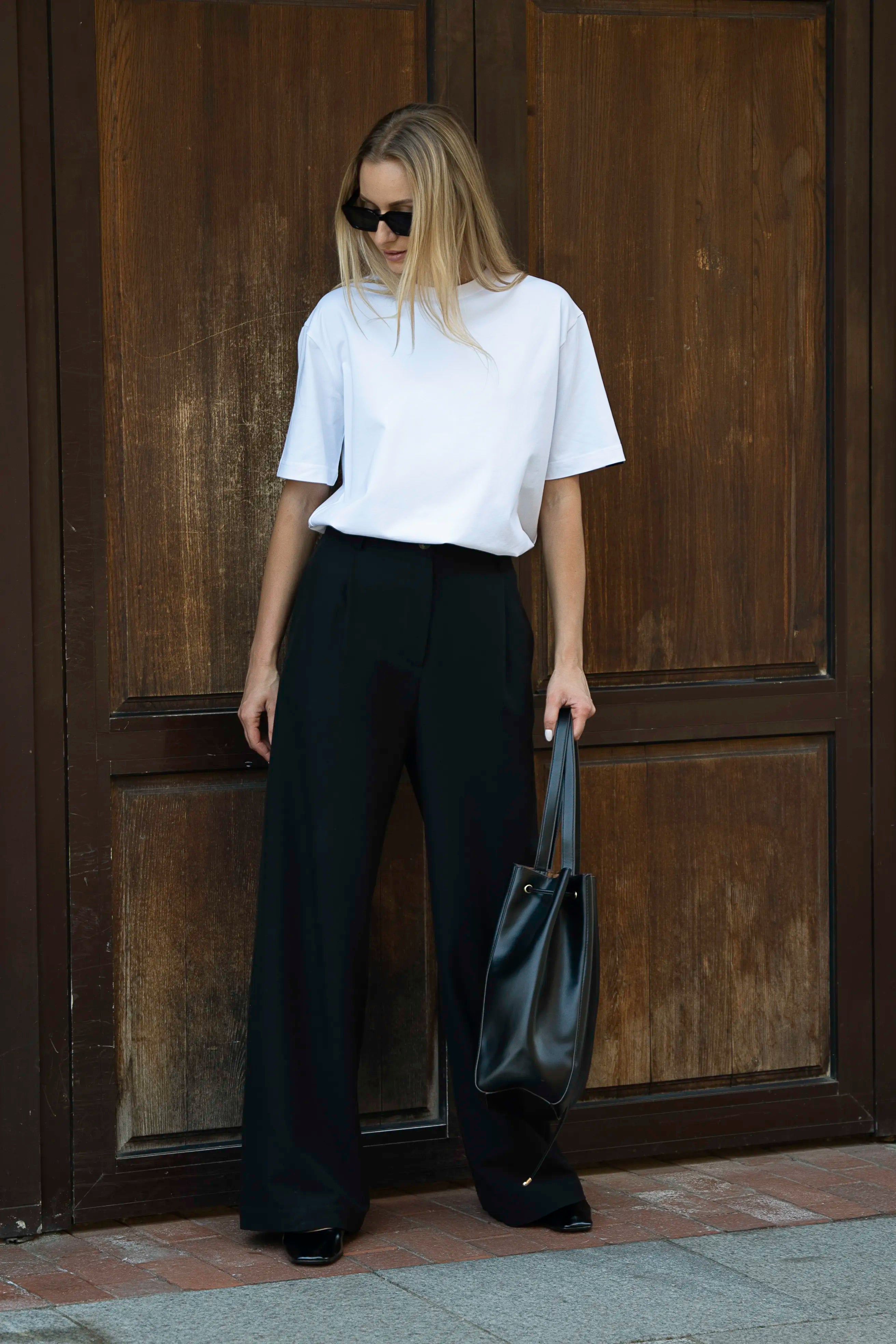 Weißes Oversize-T-Shirt und schwarze Hose mit Taschen, ein Outfit für Damen