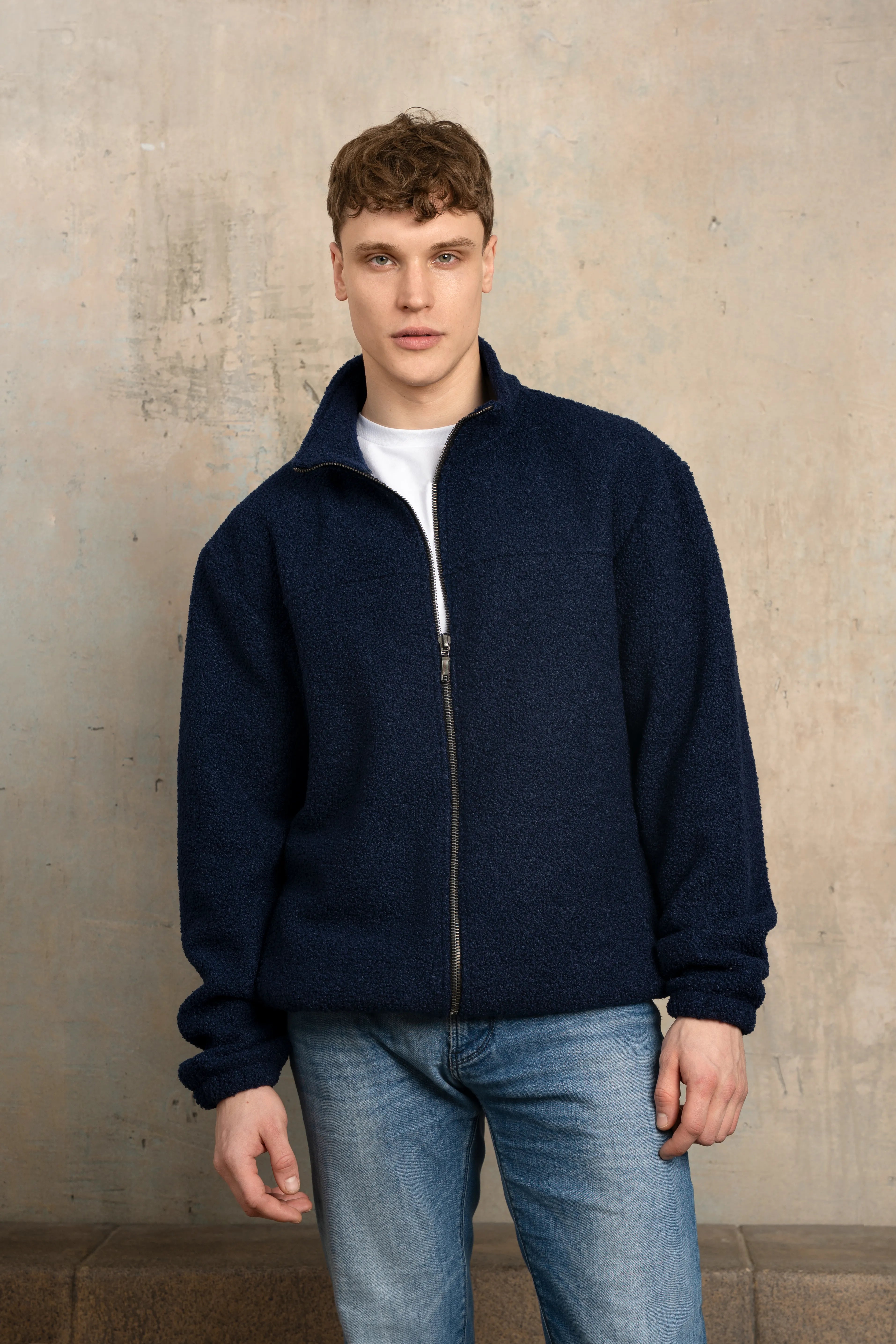 Tamsiai mėlynos spalvos vyriškas džemperis su pilno ilgio užtrauktuku, stačia apykakle, ilgomis rankovėmis ir vaizdu iš priekio