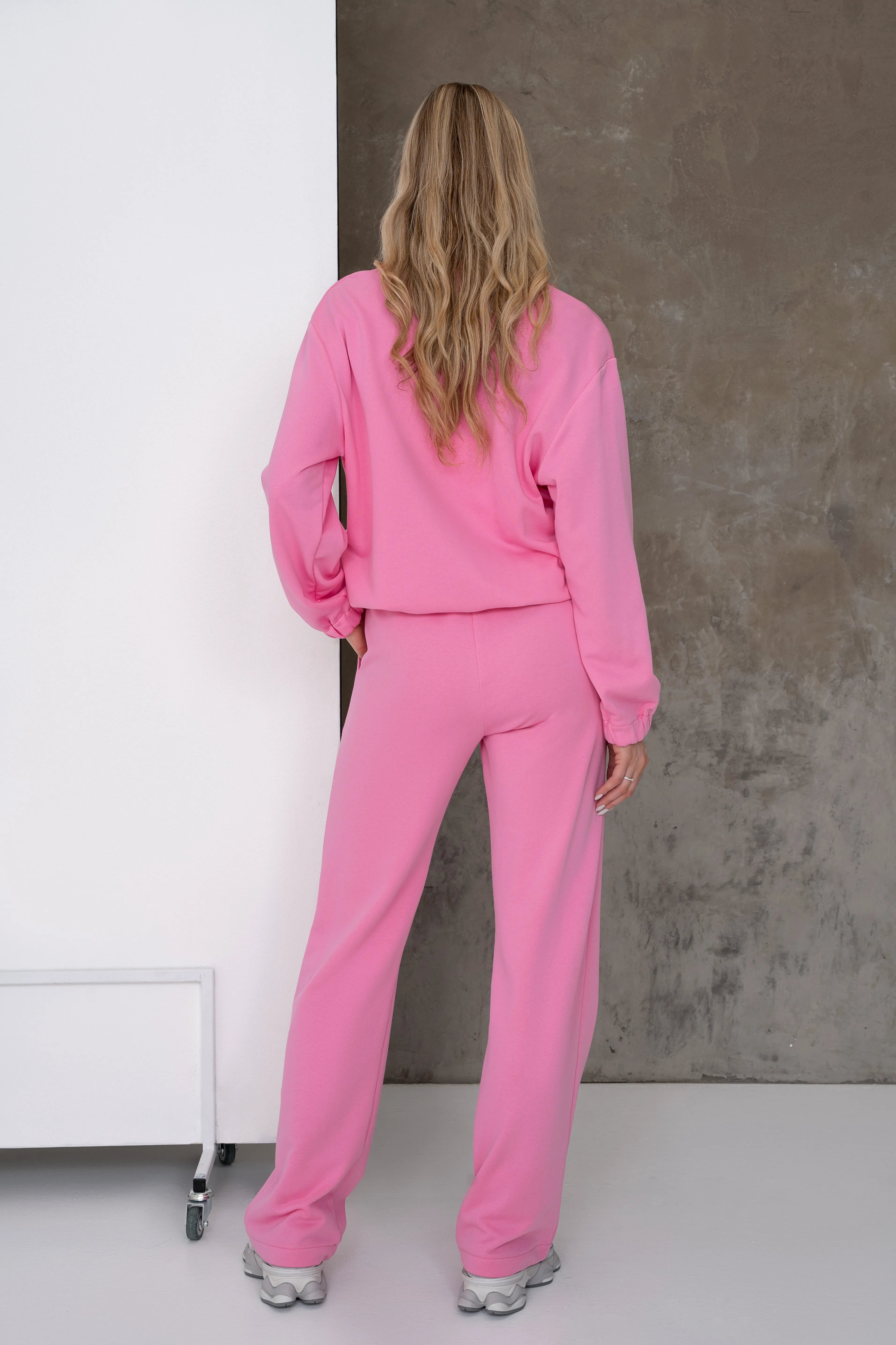 Rožinis moteriškas laisvalaikio treningas su nuleistais pečiais, reguliuojama gumelė džemperio apačioje ir tiesiomis laisvo kritimo kelnėmis, vaizdas iš nugaros