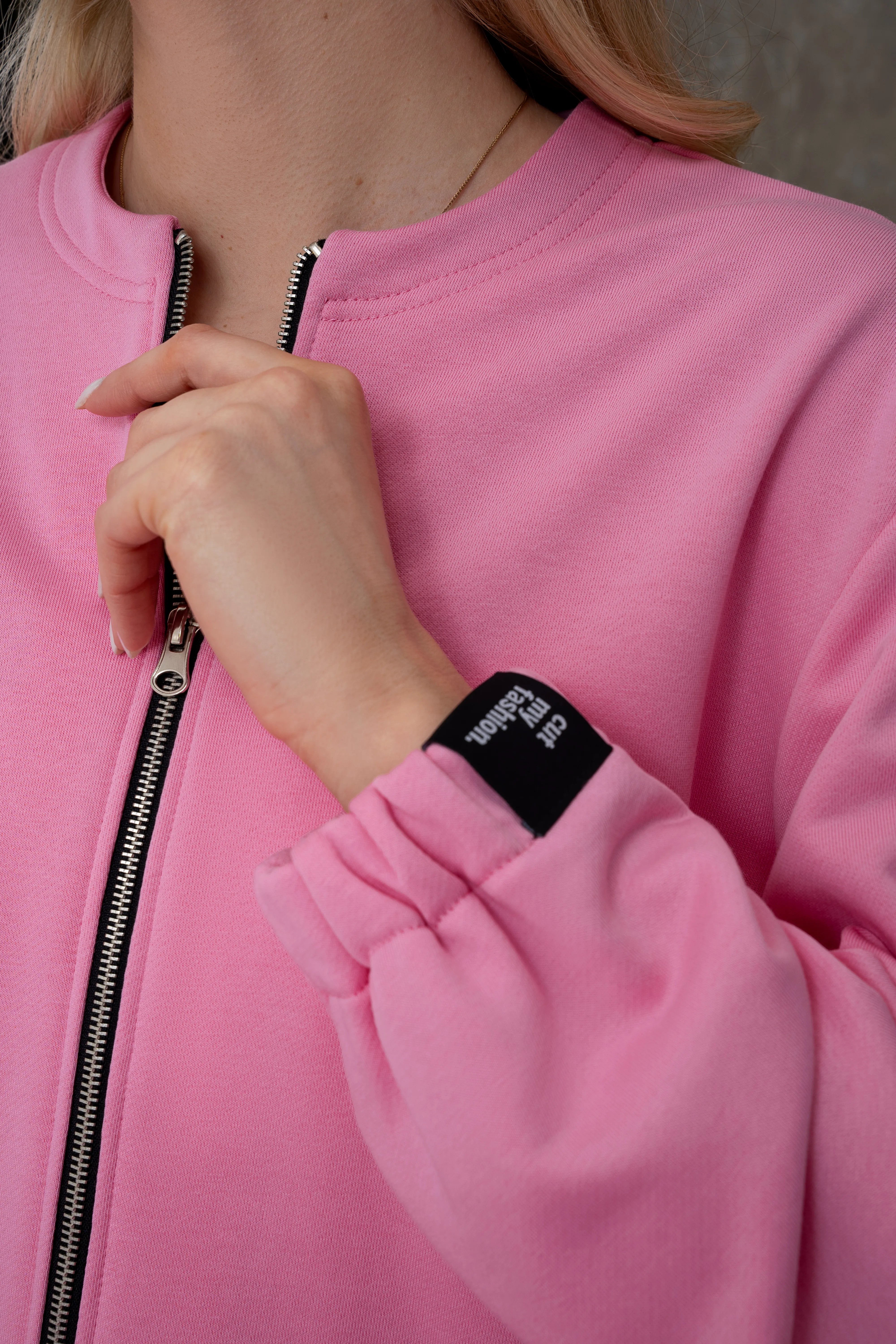 Rožinis moteriškas laisvalaikio džemperis su metaliniu pilno ilgio užtrauktuku, elastingu surauktu rankogaliu ir juoda cutmyfashion etikete, detalės vaizdas