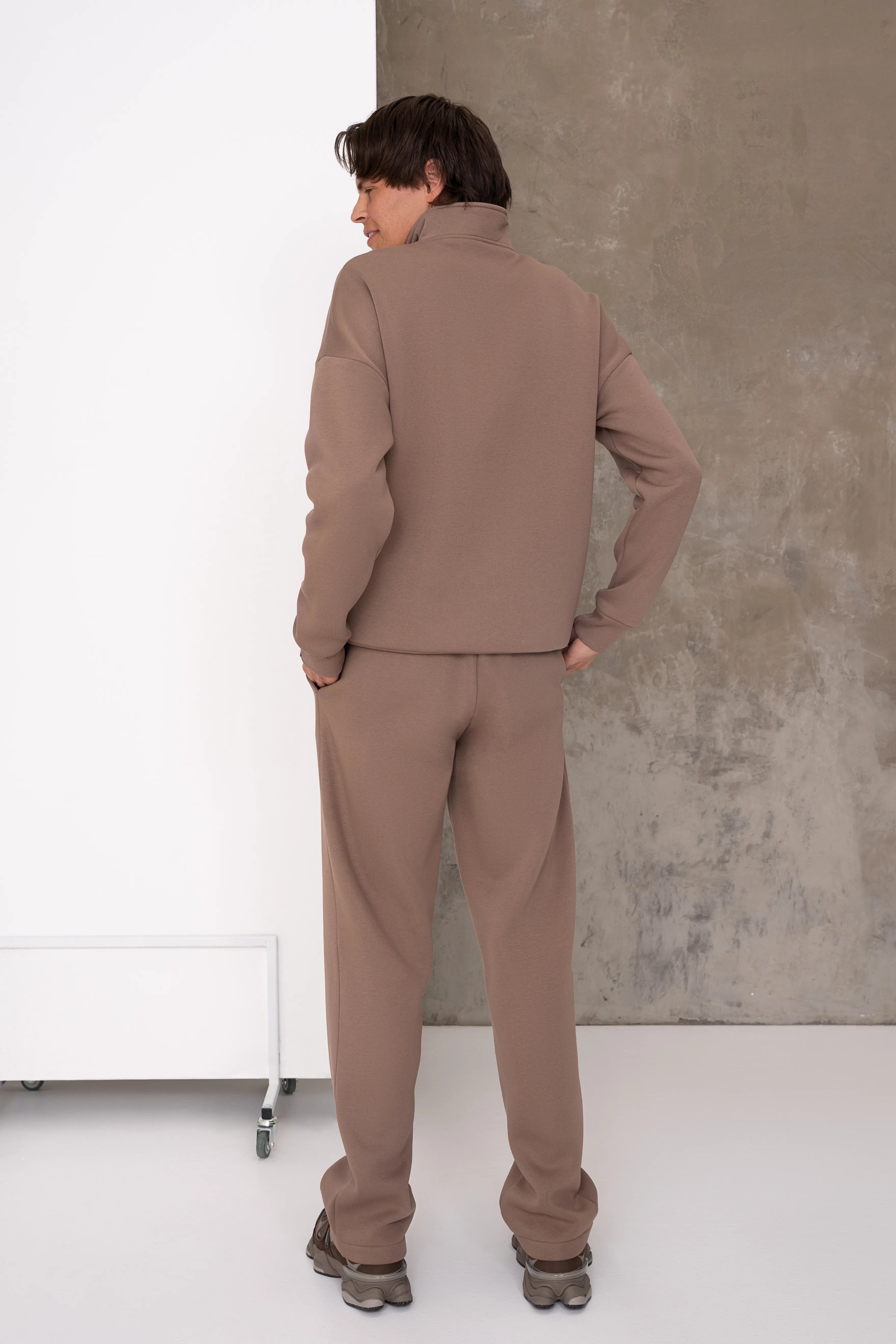 Latte spalvos vyriškas laisvalaikio treningas su laisvo kritimo džemperiu, ribo apdaila rankogaliuose ir apačioje bei tiesiomis kelnėmis, vaizdas iš nugaros