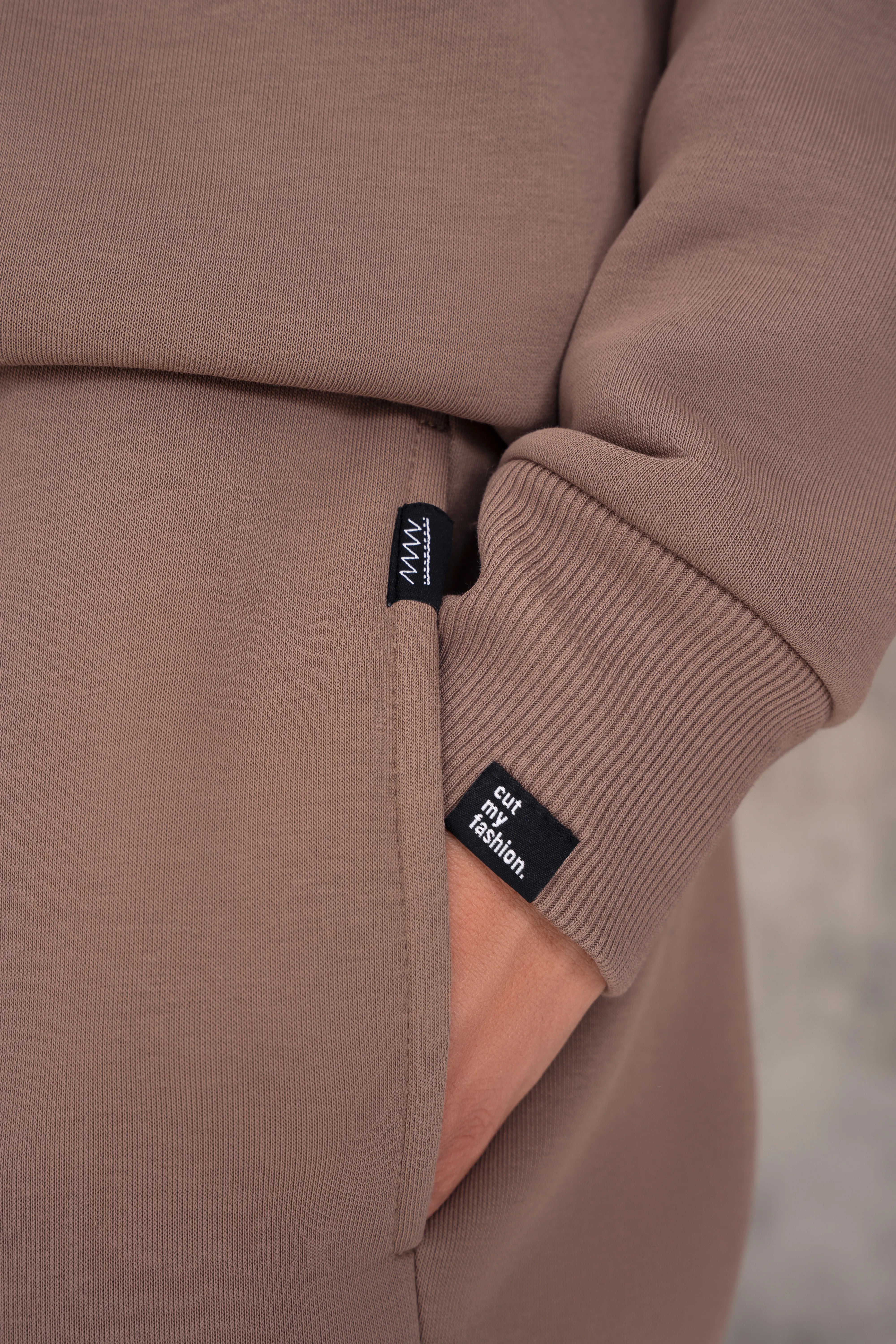 Latte spalvos vyriškas laisvalaikio džemperis su tampraus ribo rankogaliu, juoda cutmyfashion etikete ir švelnia struktūrine medžiaga, detalės vaizdas