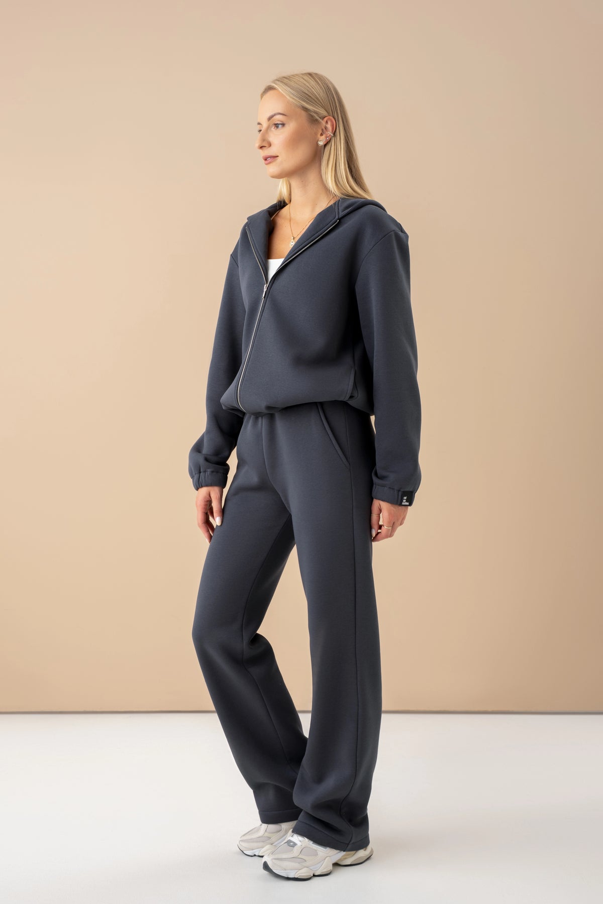 Ein dunkelgraues Trainingsset von cutmyfashion, das Model ist seitlich gedreht, Studioaufnahme