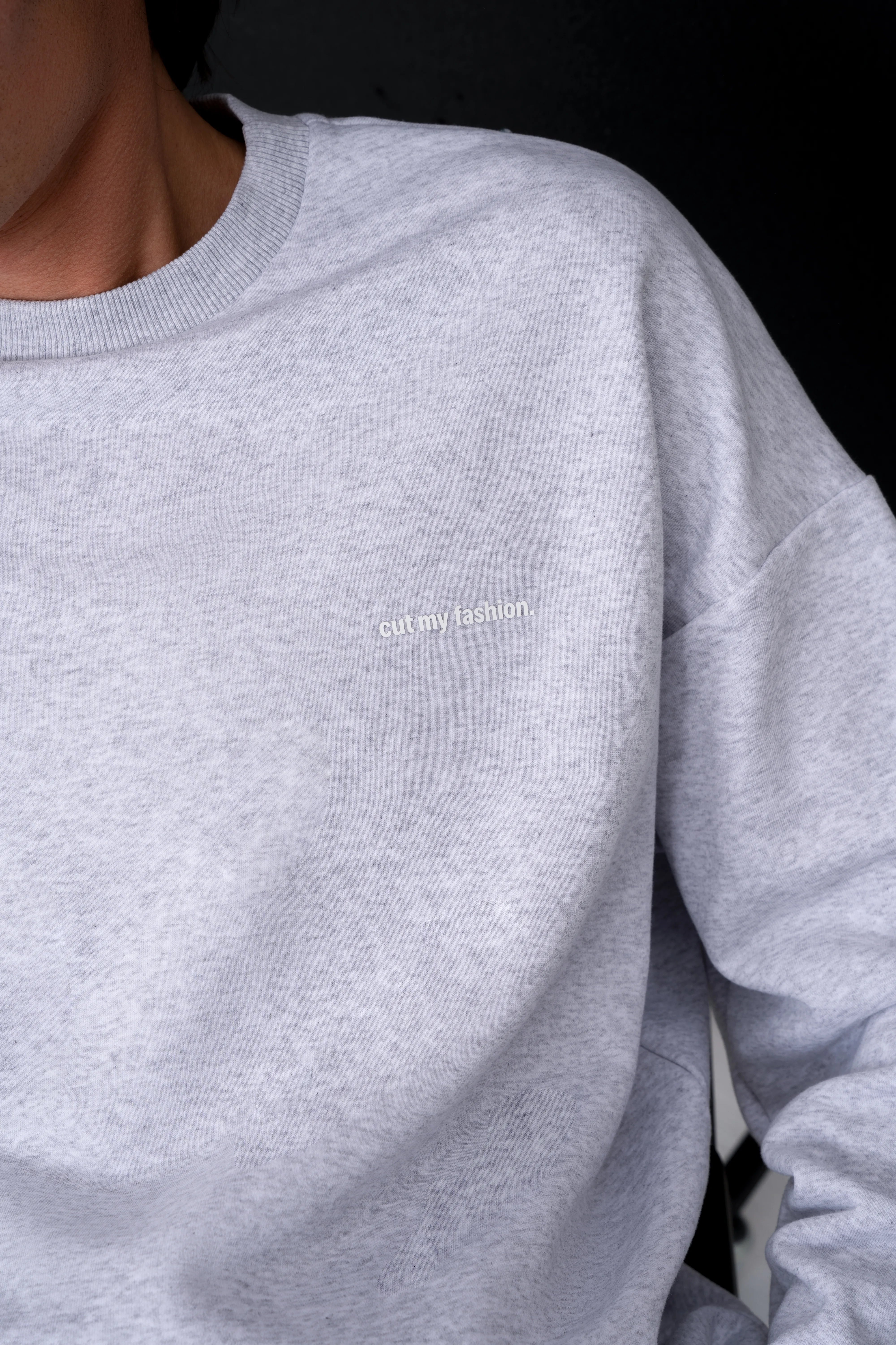 Šviesiai pilkas vyriškas džemperis su apvalia apykakle ir nuleistais pečiais, subtilus cut my fashion logotipas priekyje, medvilnės ir poliesterio audinys be pūkelio
