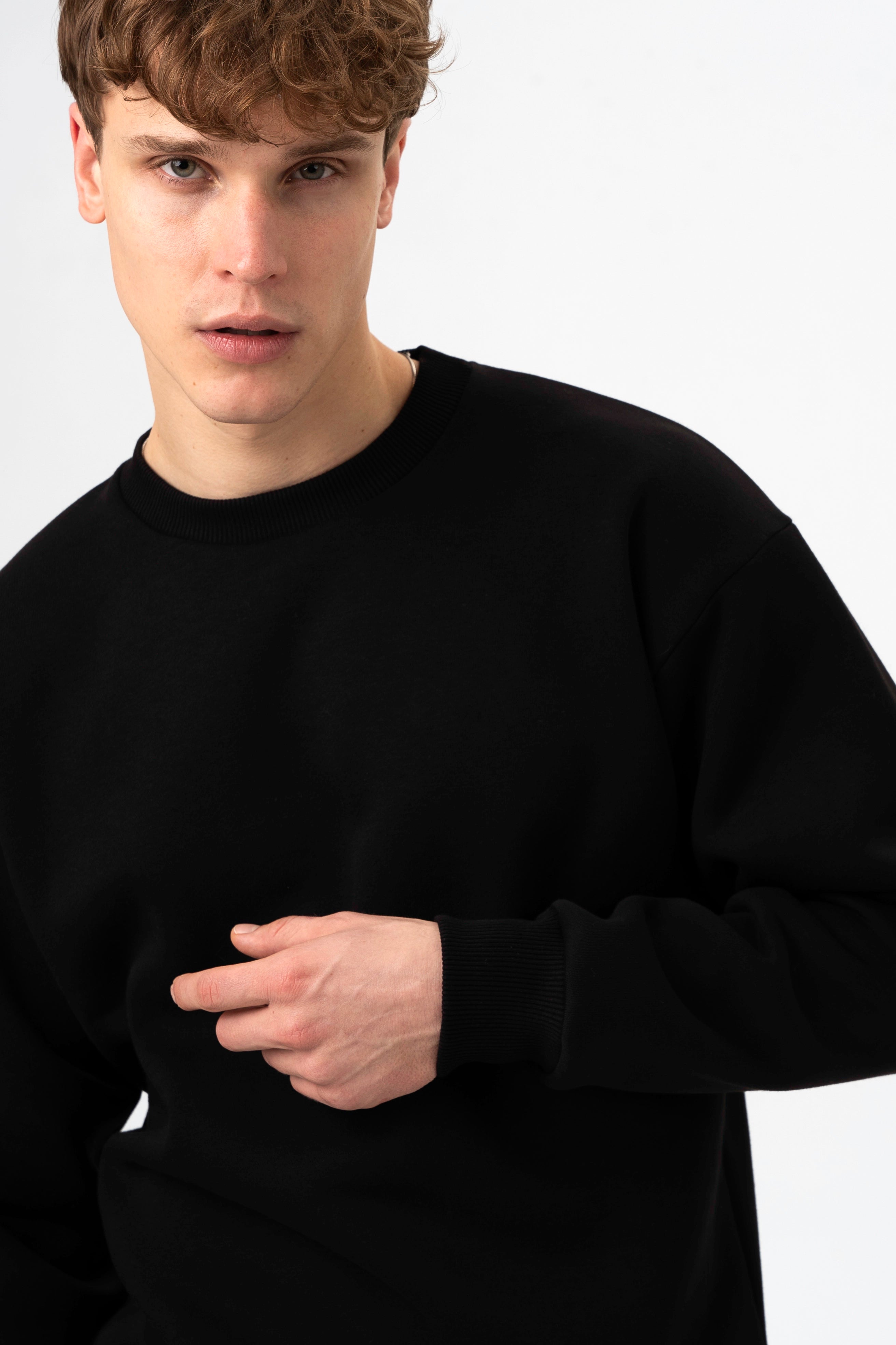 Vaikinas pozuoja kaip dėvi laisvalaikio džemperį juodos spalvos