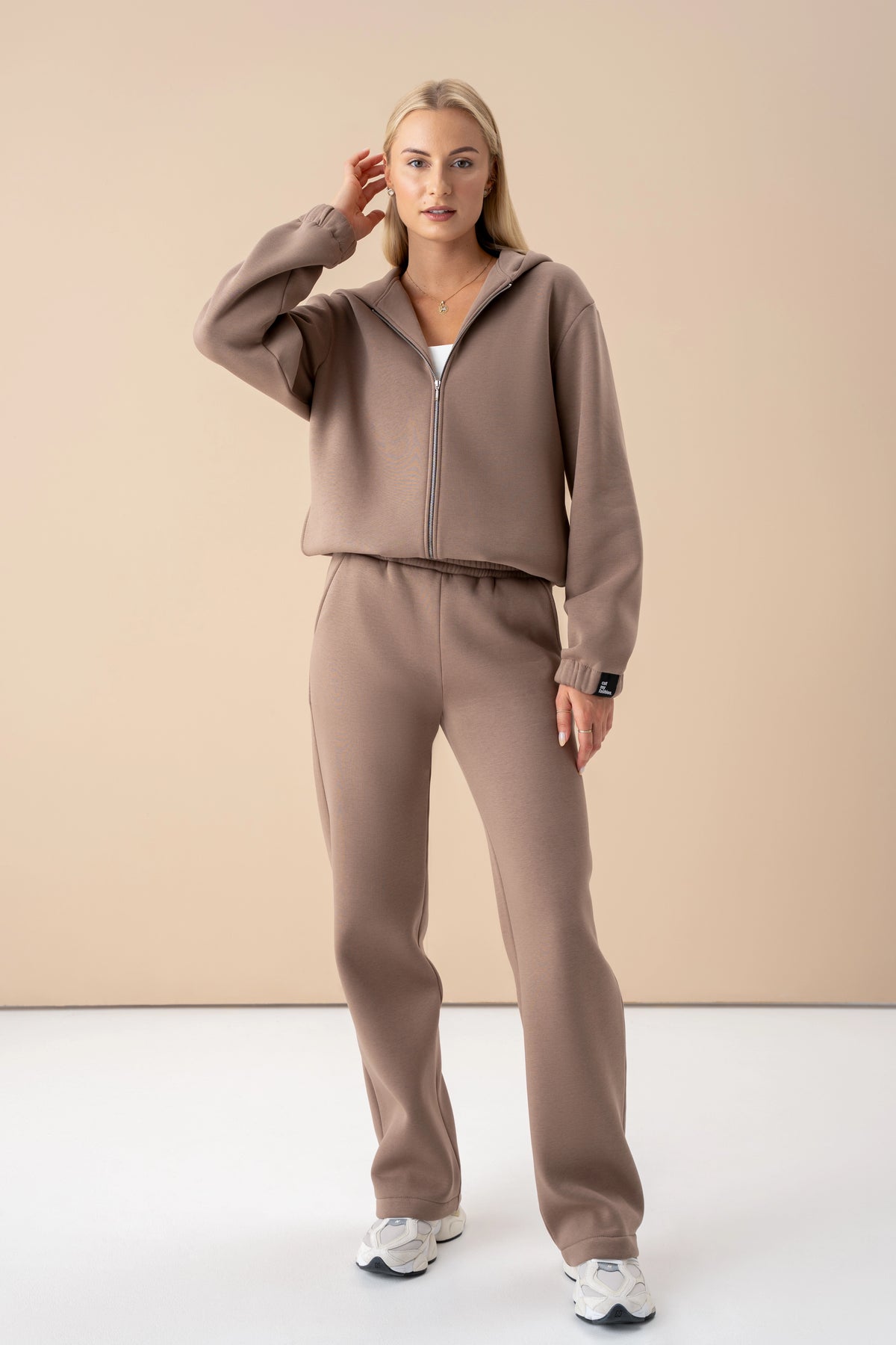 Ein brauner Freizeitanzug aus OEKO-TEX®-zertifiziertem Stoff – warm, atmungsaktiv und bewegungsfreundlich. Nachhaltig in Litauen hergestellt.