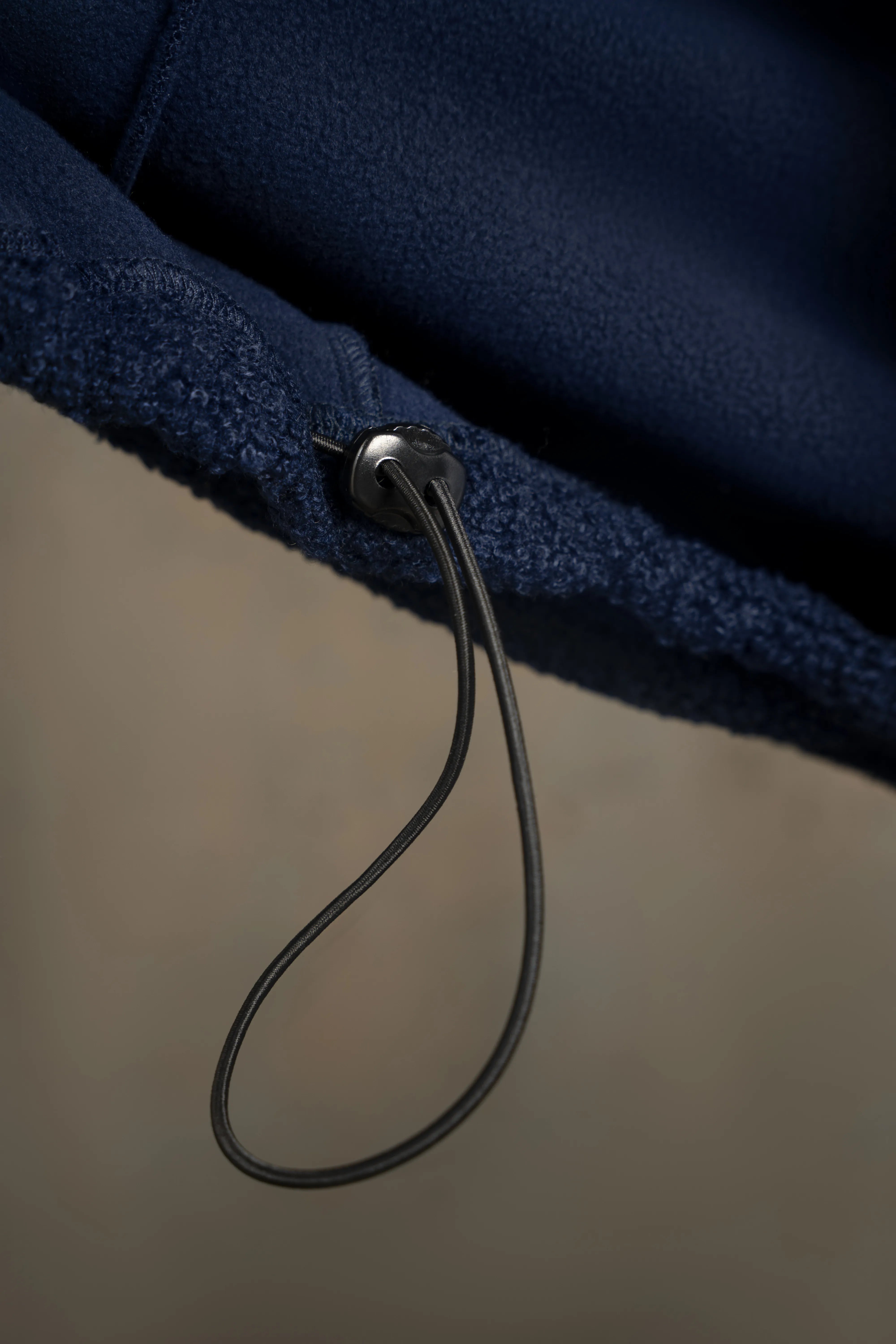 Detail der Kordel und der Naht am Saum eines dunkelblauen Herrenpullovers