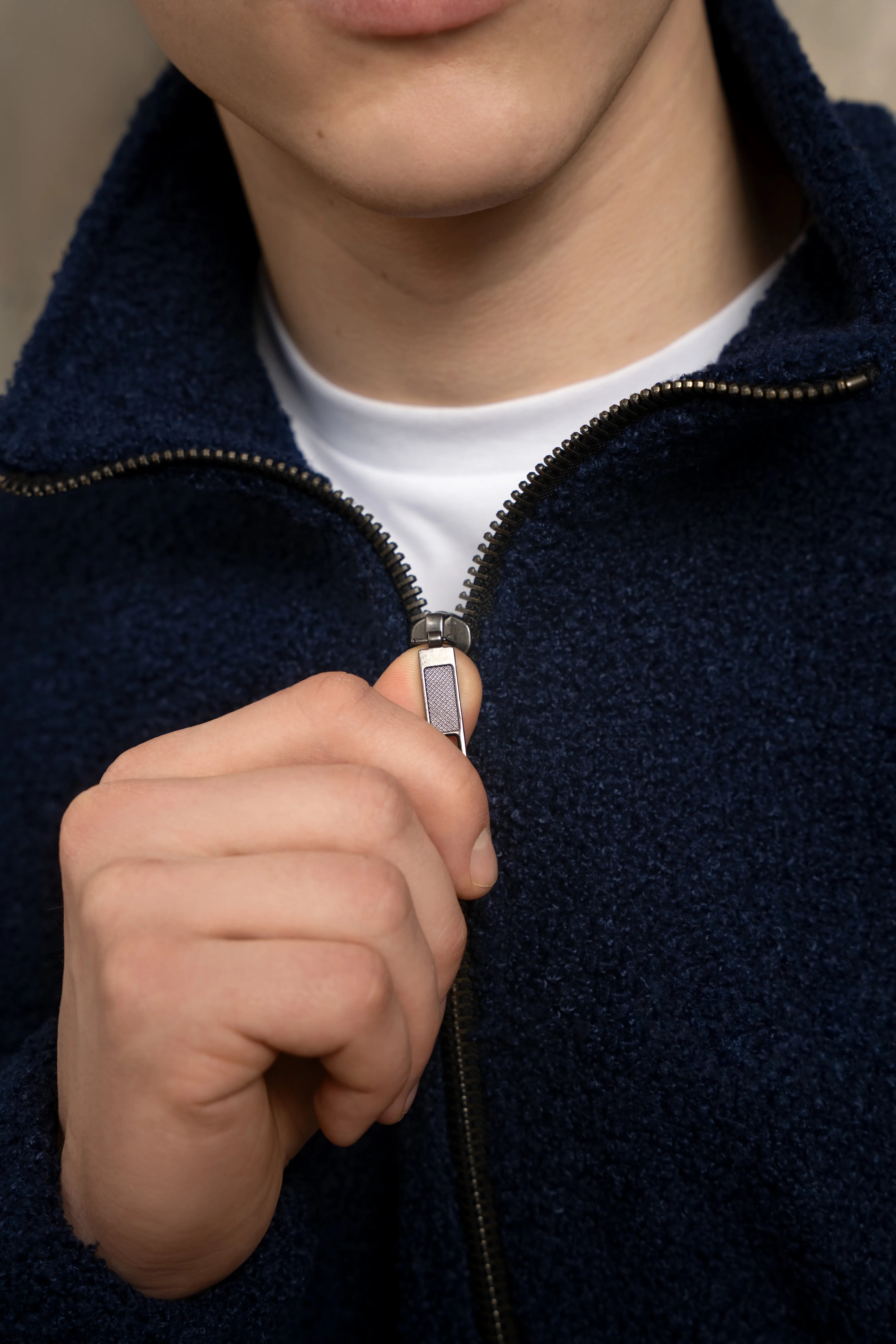 Detail des metallischen durchgehenden Reißverschlusses und des Kragens eines dunkelblauen Herrenpullovers
