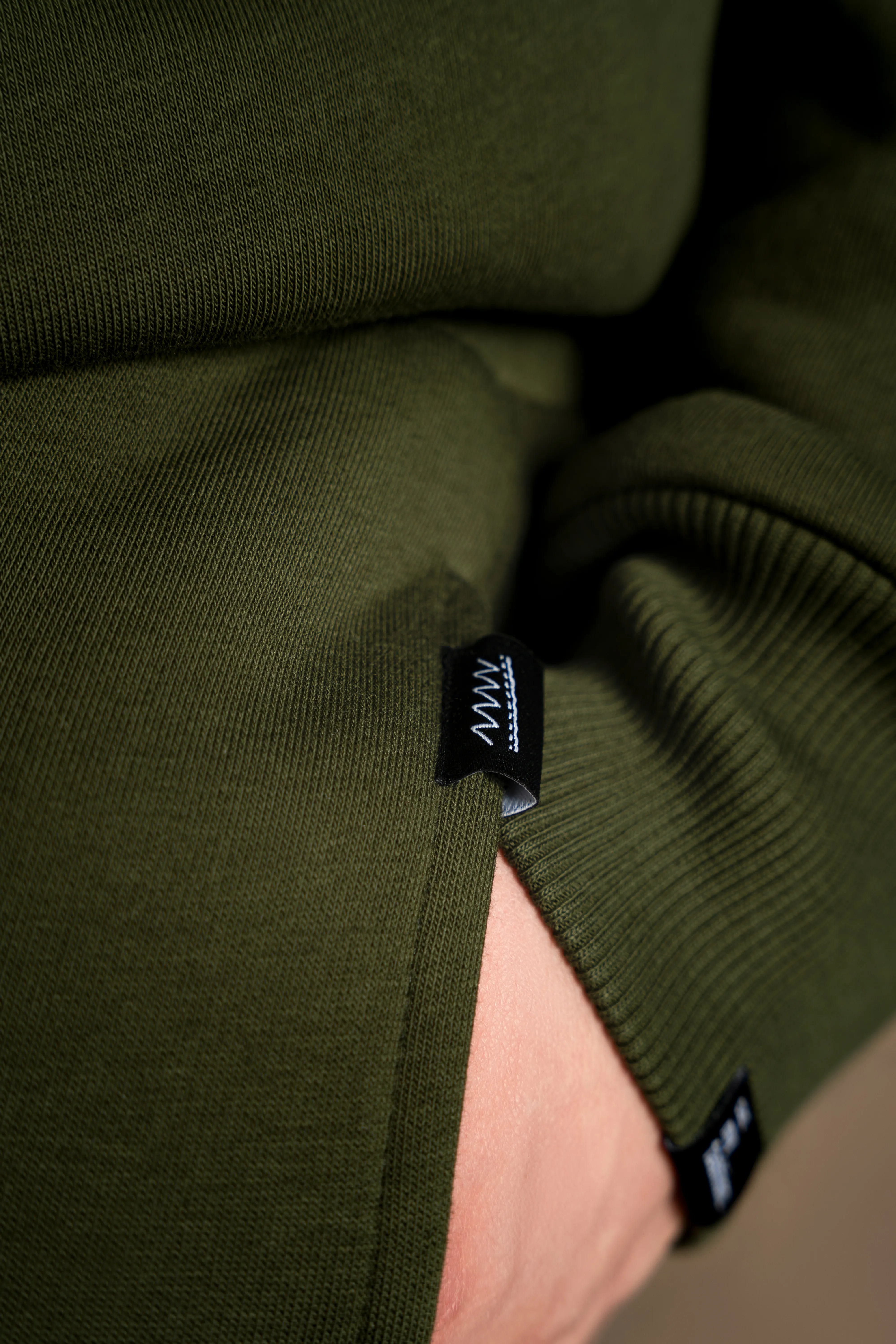 Tamsiai žalio laisvalaikio treningo audinio detalė, tinkama ramiam dėvėjimui namuose.