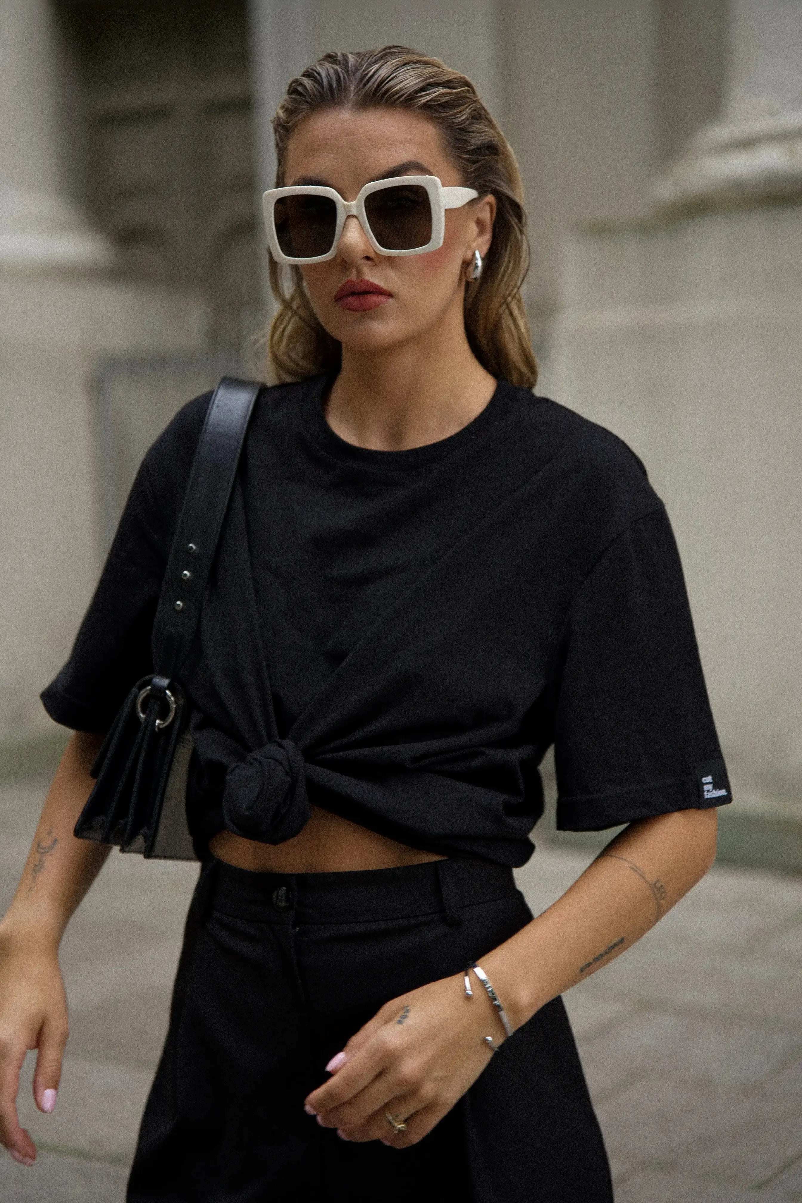 Ein schwarzes Damen-Outfit mit einem Oversize-T-Shirt und einer Hose, von der Seite gesehen