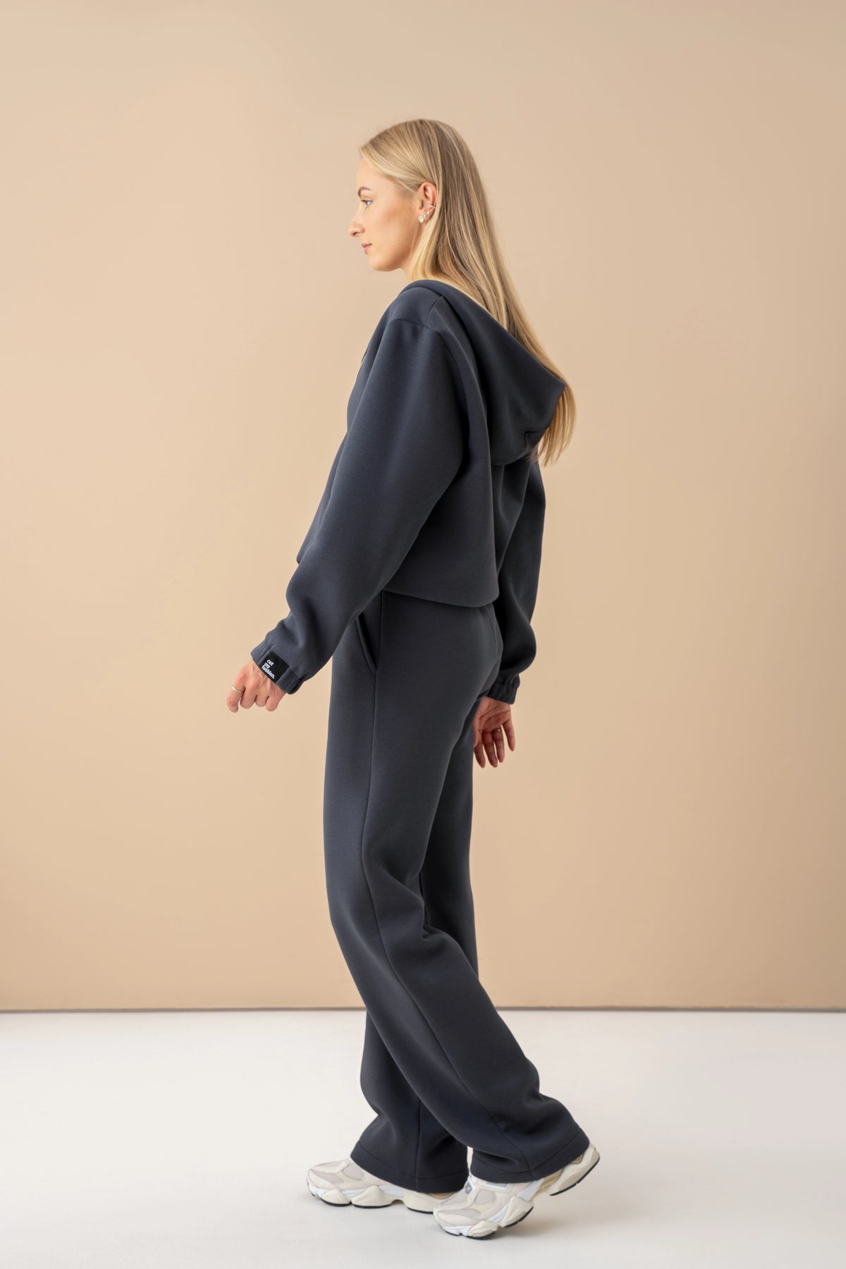 Ein Model in dunkelgrauen Freizeit-Trainingshosen von Cutmyfashion steht vor einem hellen Studiohintergrund und hat sich zur Seite gedreht